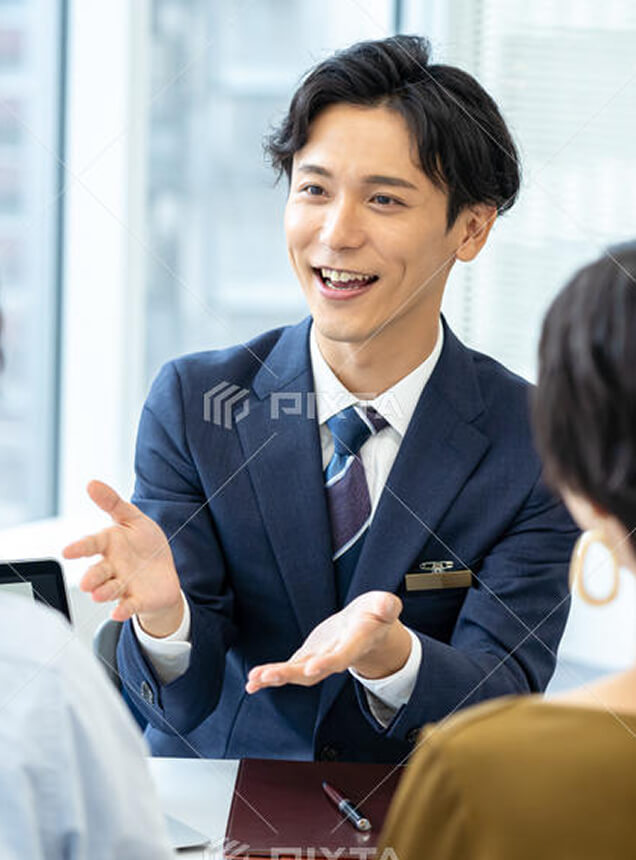 商談席で笑顔で打ち合わせを行う男性社員の様子