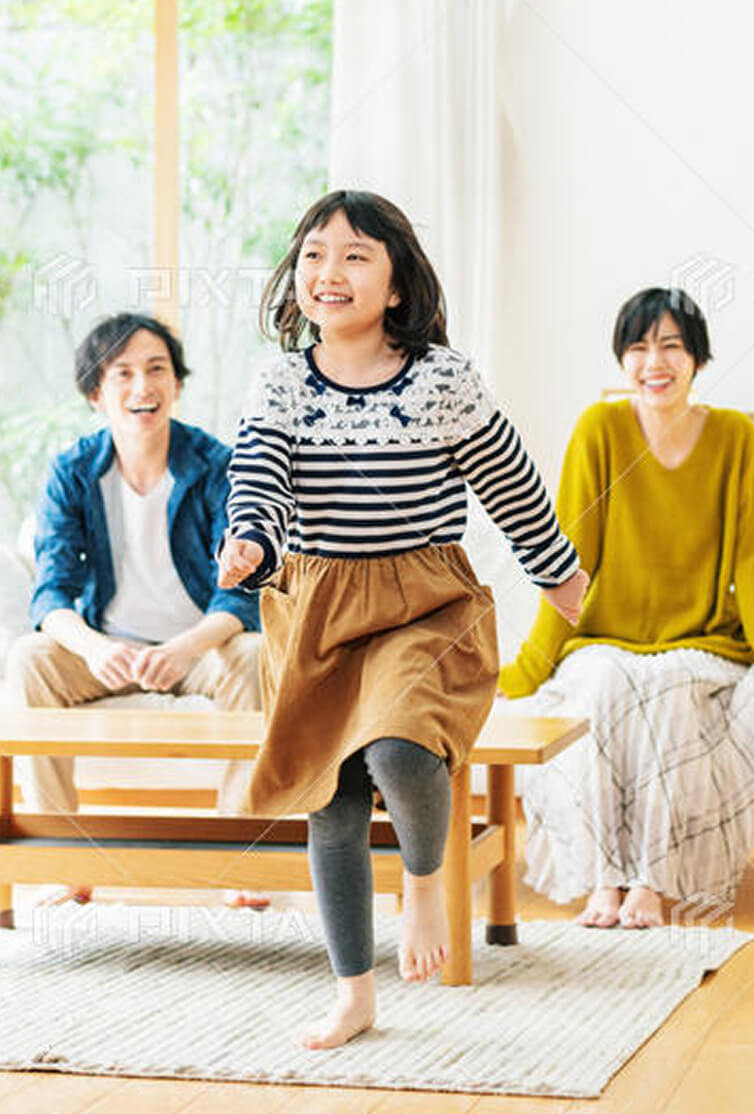 リビングで走る女の子を笑顔で見守る両親
